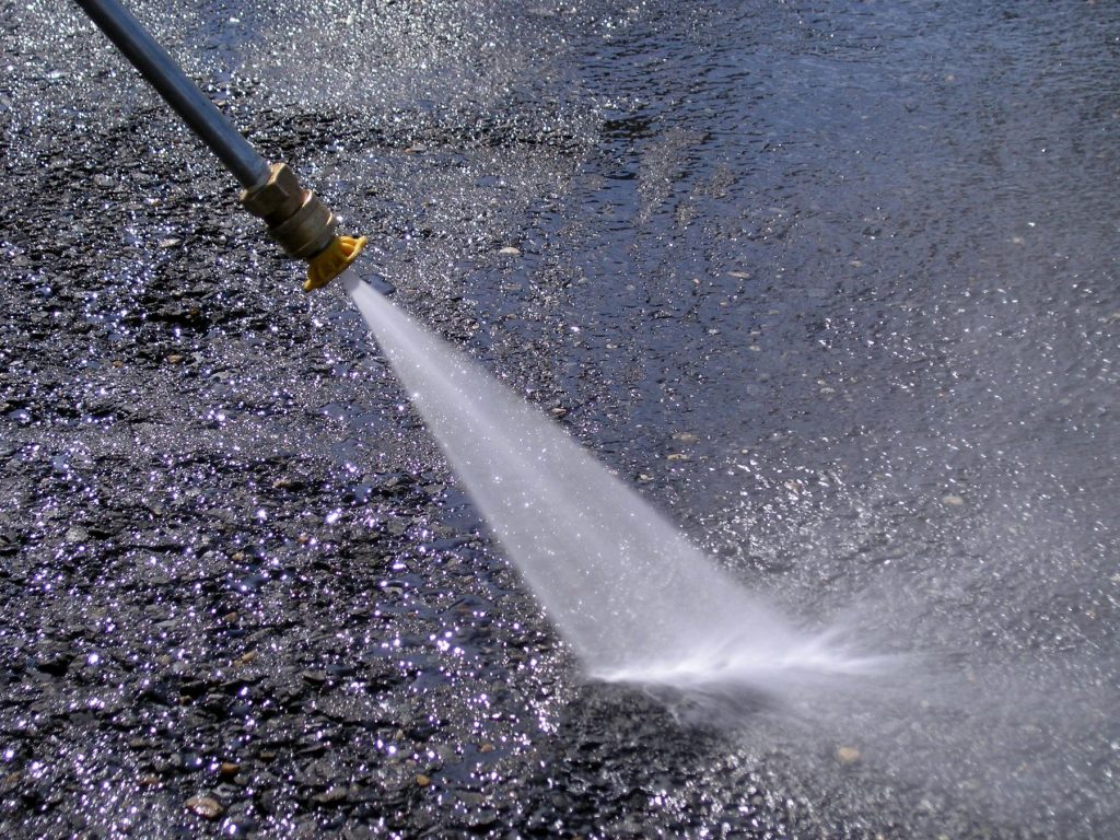Pressure washer wand spraying a dirty surface